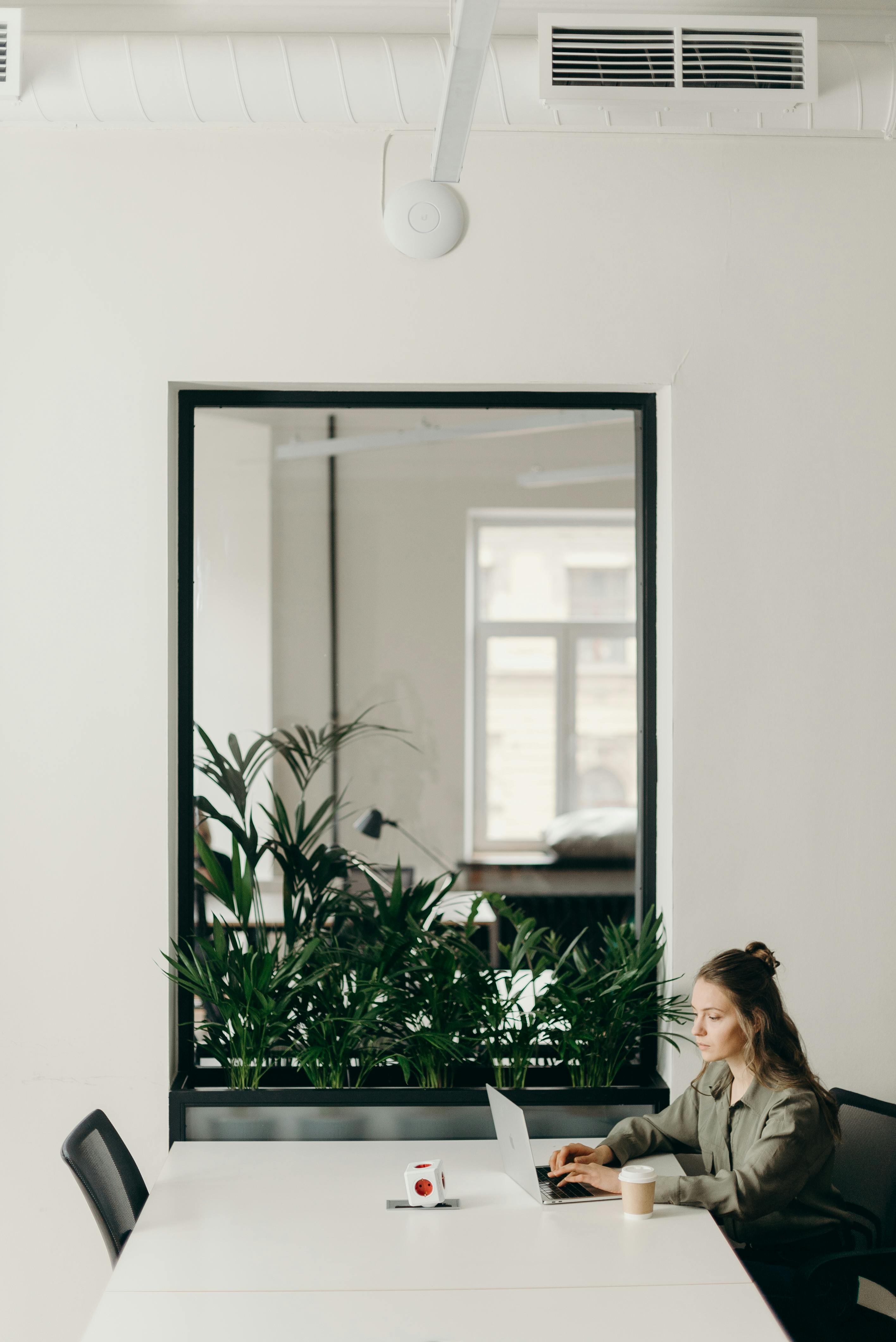 photo of woman sitting on chair while using laptop