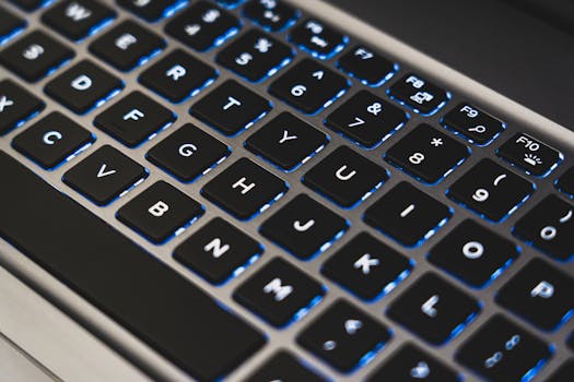 A detailed view of a backlit laptop keyboard with glowing blue lights.