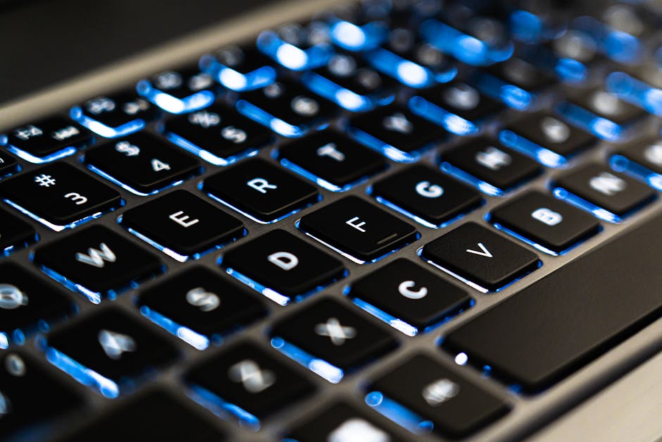 Detailed view of a backlit laptop keyboard keys with blue LED lighting for tech concepts.