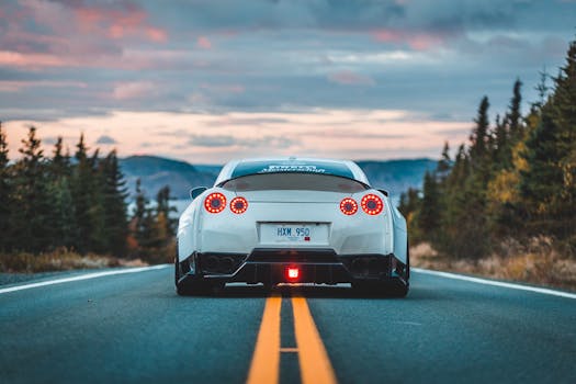 A luxury sports car driving on an empty highway, surrounded by nature at sunset.