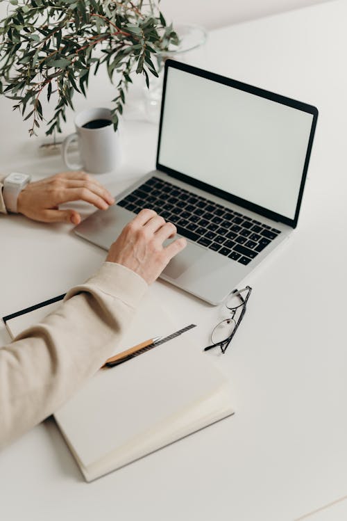 Free Person Using Macbook Pro on White Table Stock Photo