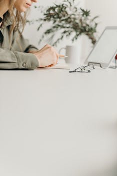 A serene home workspace featuring a tablet, paper, and coffee beside a plant.
