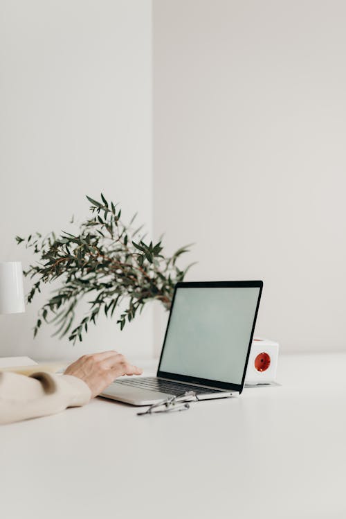 Free Person Using Laptop Computer on White Table Stock Photo