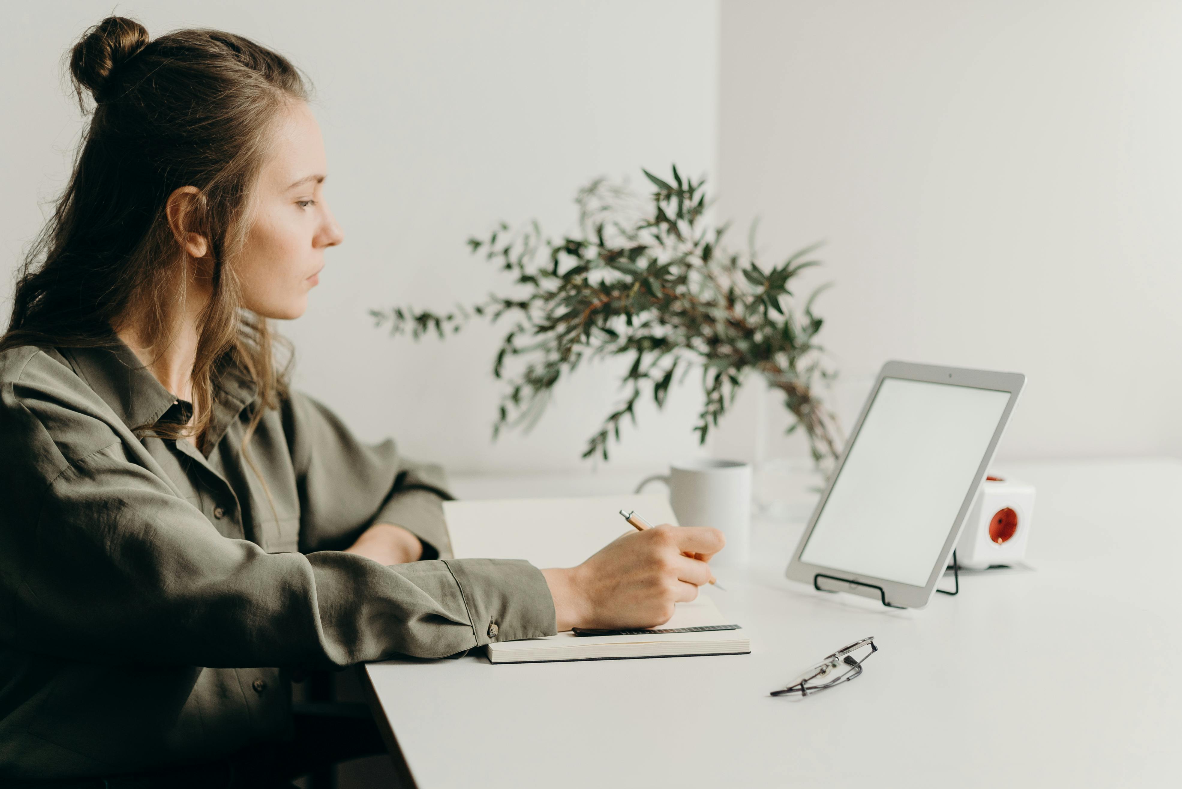 woman in gray coat using white laptop computer