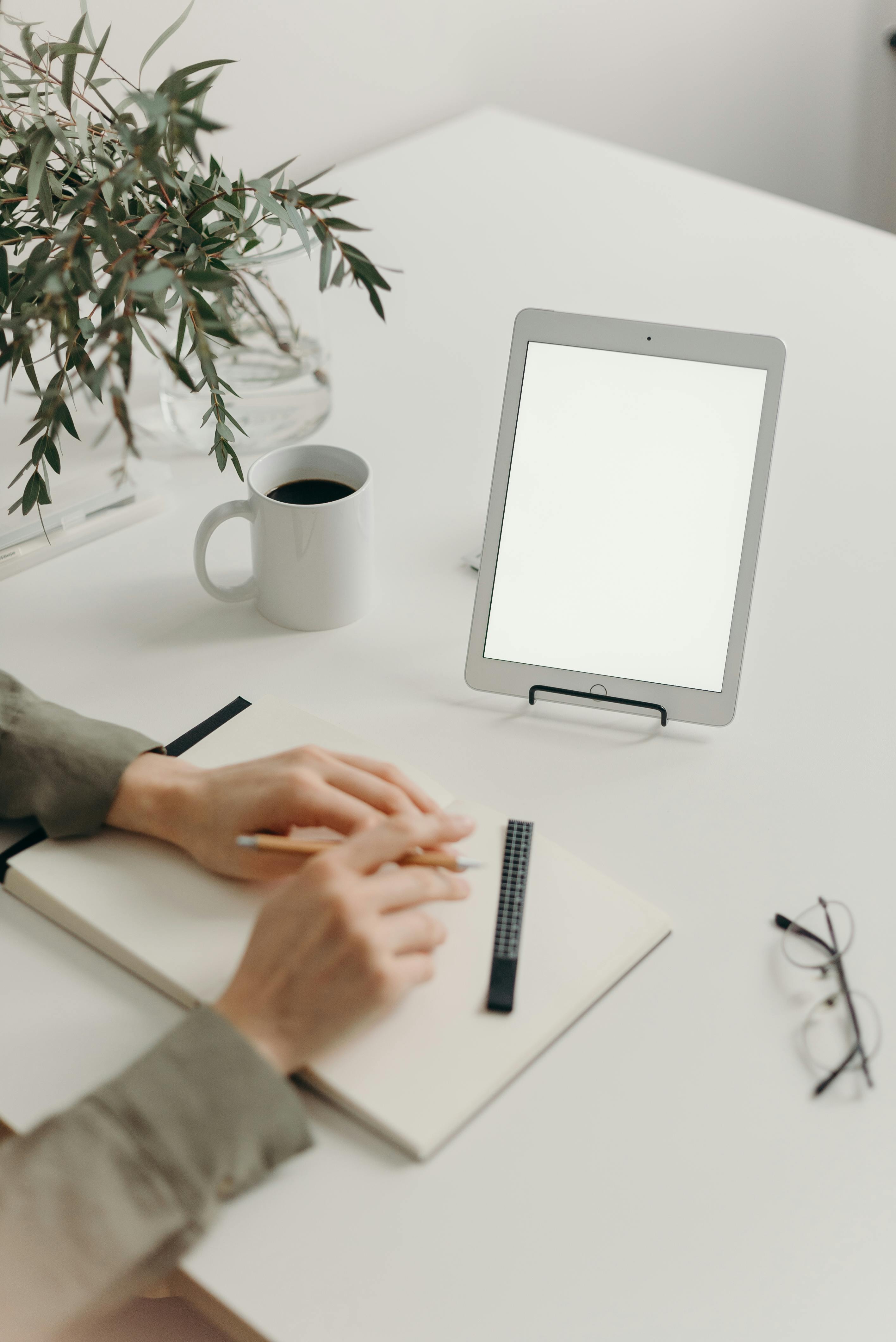 person writing on white paper on white table