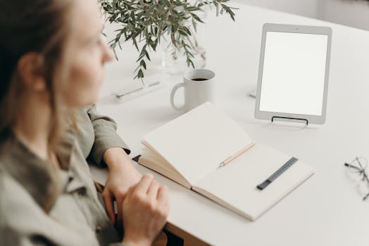 Woman sitting at a desk with blank tablet and notebook in a modern home office setting.