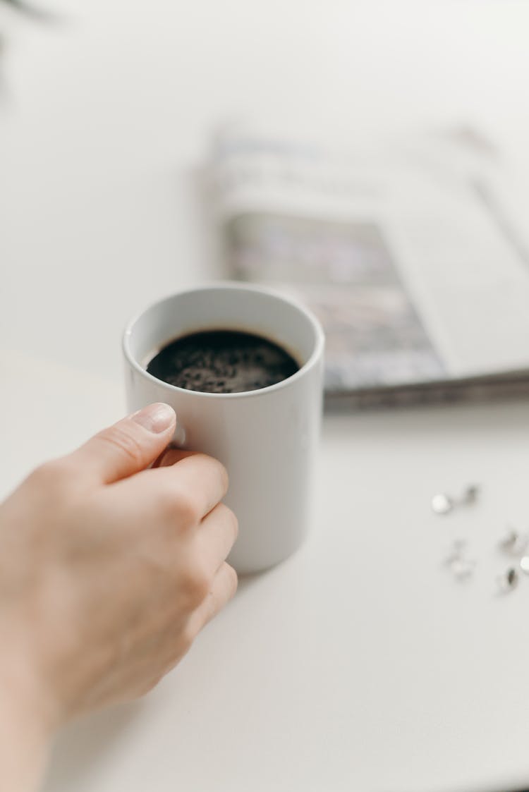 Person Holding White Ceramic Mug With Black Coffee