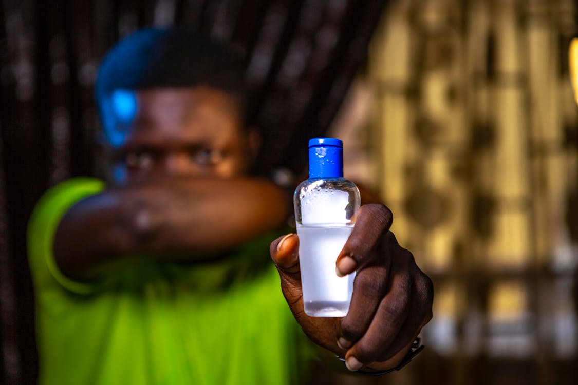 Shallow Focus Photo of Man Holding Bottle With Sanitizer