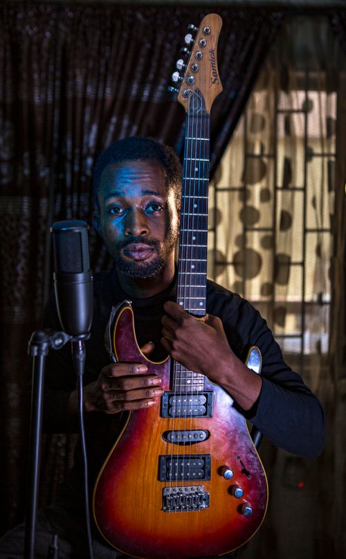Free Portrait of a black male musician with electric guitar, pensive and serious expression. Stock Photo