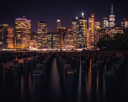 Stunning urban skyline at night with illuminated skyscrapers reflecting on the water, capturing the vibrant city life.