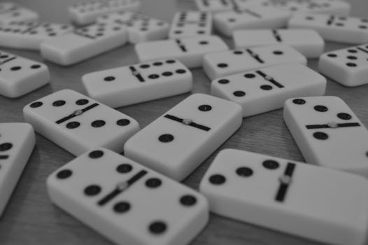 Scattered monochrome dominoes on a flat surface emphasizing leisure and strategy.