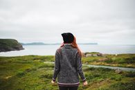 红发女子独自站在那儿，欣赏着美丽的海岸景色