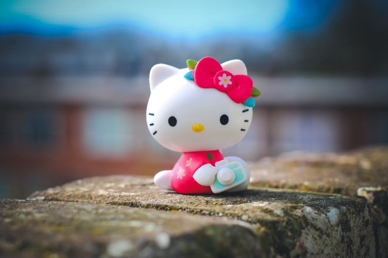 adorable hello kitty toy figurine posed on a brick surface with a blur