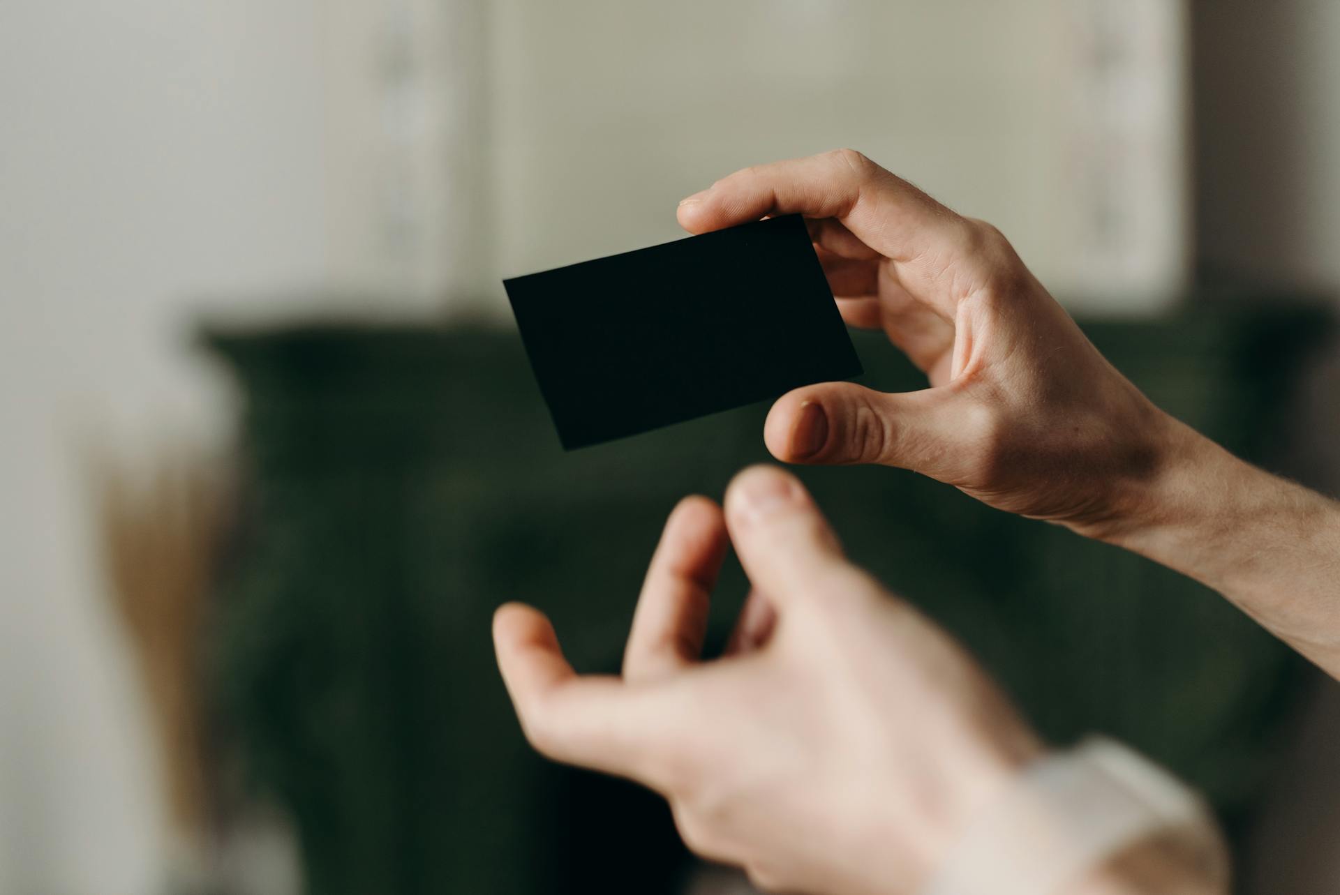 Close-up photo of hands holding a blank black card, perfect for mockup or template purposes.