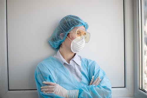Woman in Blue Scrub Suit Wearing White Mask