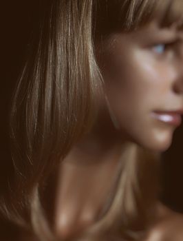 Artistic portrait highlighting silky smooth blonde hair texture with shallow focus.
