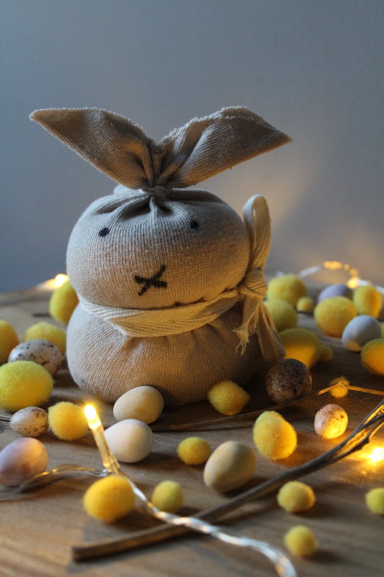 Easter Bunny Toy Placed On Table Among Scattered Decorative Eggs