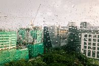 透过雨水覆盖的窗户，现代城市建筑的景色映入眼帘，营造出一种忧郁的氛围