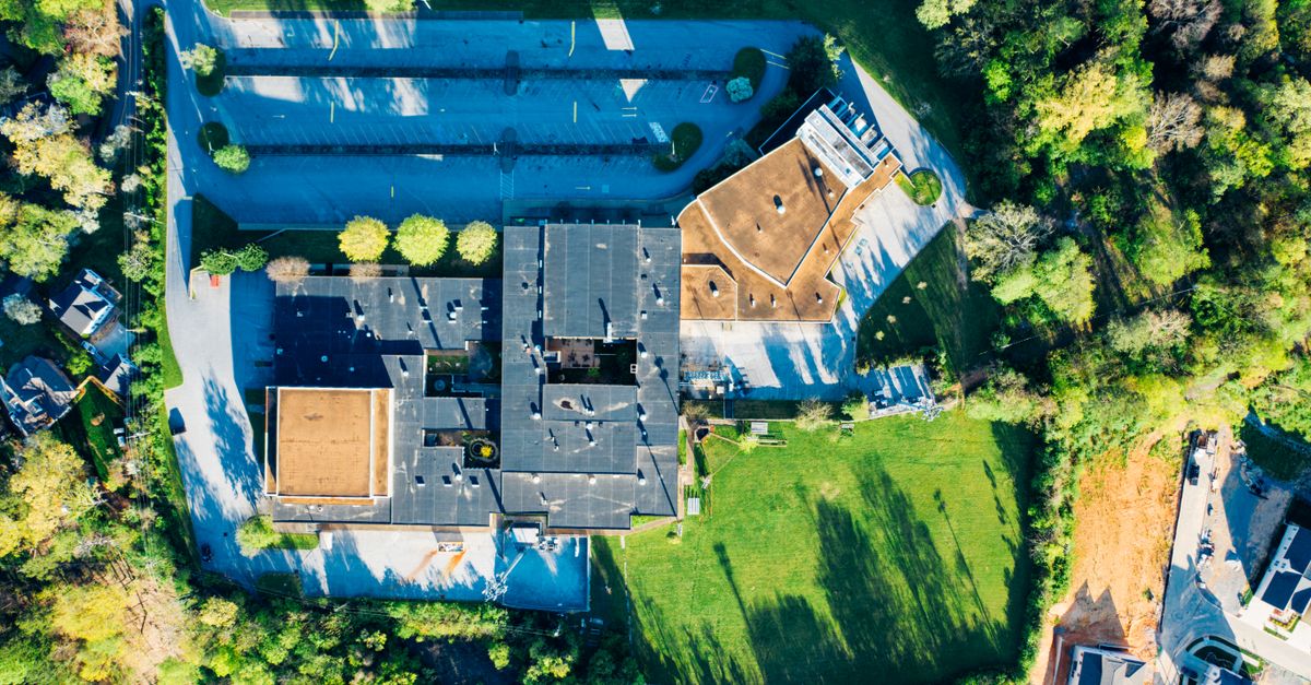 Drone view of contemporary residential house with outdoor swimming pool and big greet territory with lush trees on sunny day