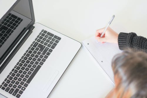 Person Writing on Notebook