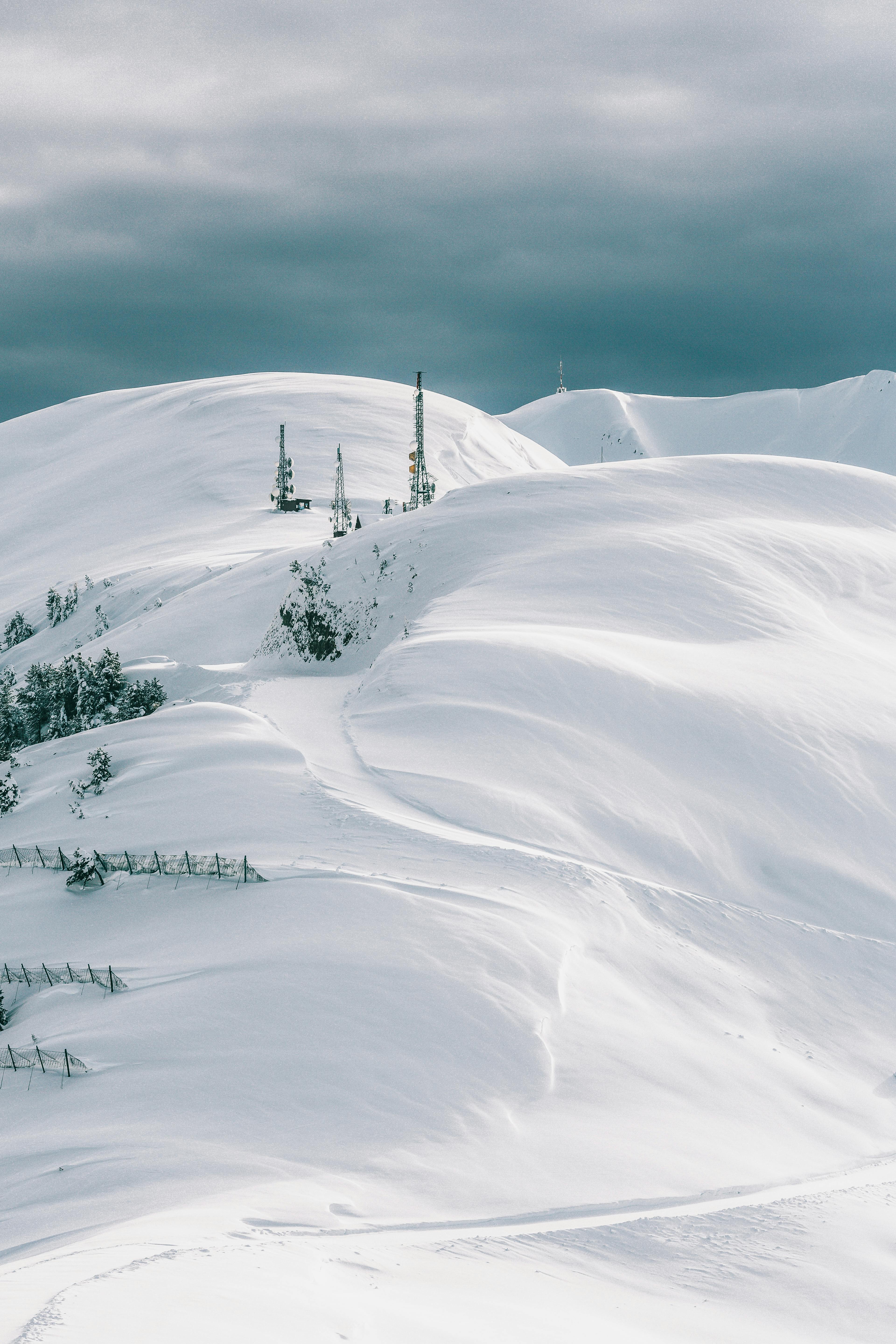 Prescription Goggle Inserts - Breathtaking view of snow-covered mountains with communication towers under a cloudy sky, showcasing winter's beauty.