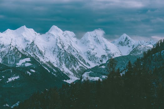 Peaceful snowy mountain range under cloudy sky, perfect nature scenery.