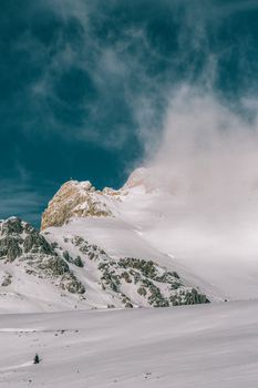 蔚蓝的天空下，白雪覆盖的山峰笼罩在雾中，景色宁静