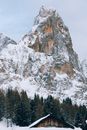 冬日景象宁静，白雪皑皑的山峰间，松树掩映着一座乡村小屋