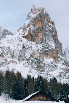冬日景象宁静，白雪皑皑的山峰间，松树掩映着一座乡村小屋