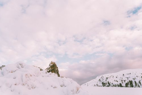 Free A serene view of snow-covered mountains under a cloudy sky in winter, capturing nature's tranquility. Stock Photo