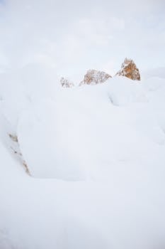 Tranquil snowy landscape with mountain peaks emerging from fresh snow, capturing winter's beauty.