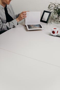 A person reading a book in a minimalist home office setting.