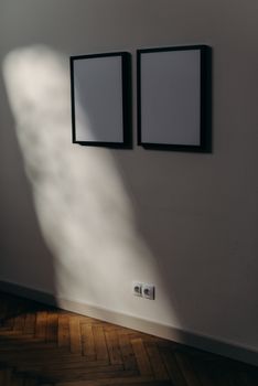 阳光明媚的墙上挂着两件黑框艺术作品，营造出极简而现代的氛围