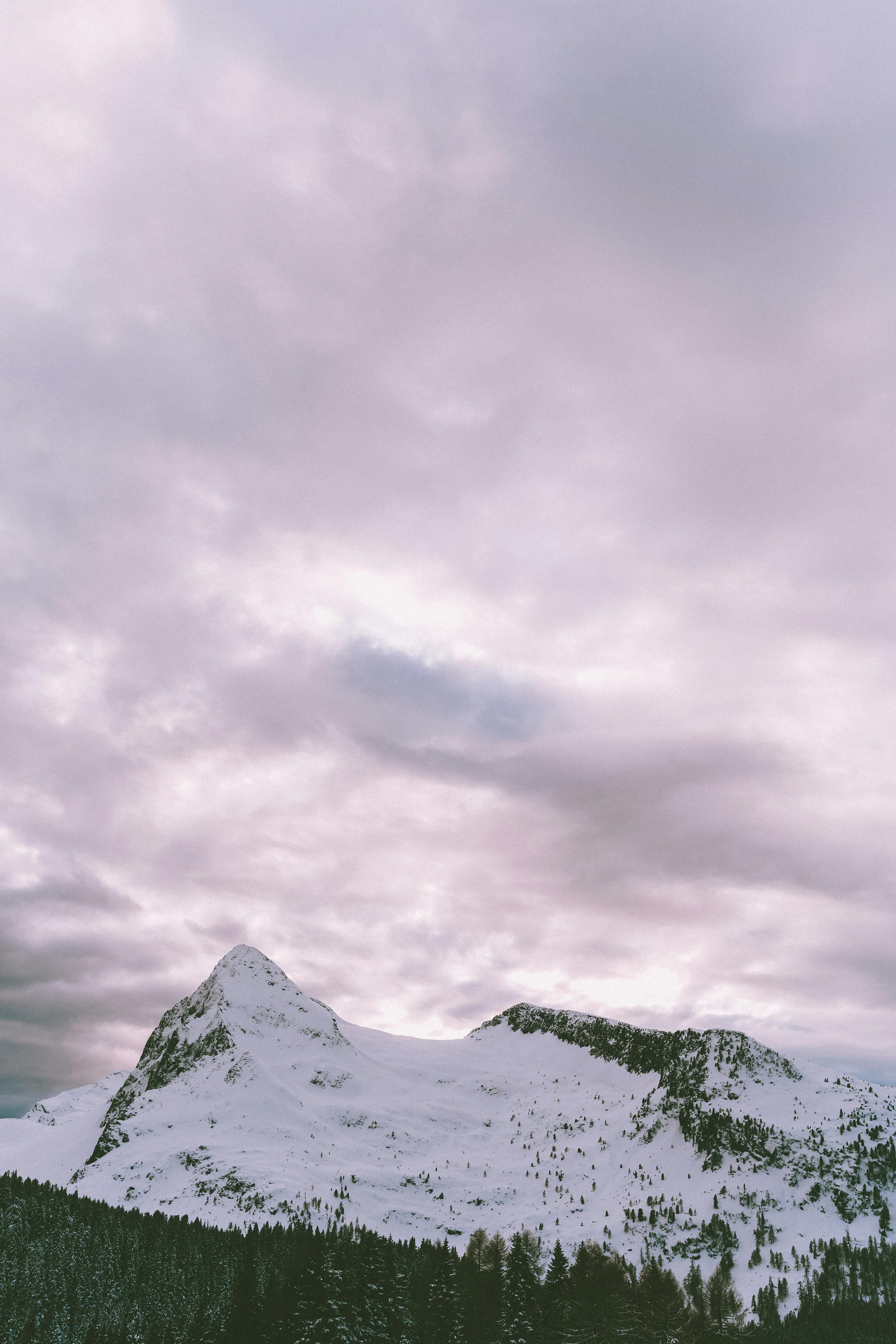 photo of snow covered mountains under cloudy sky