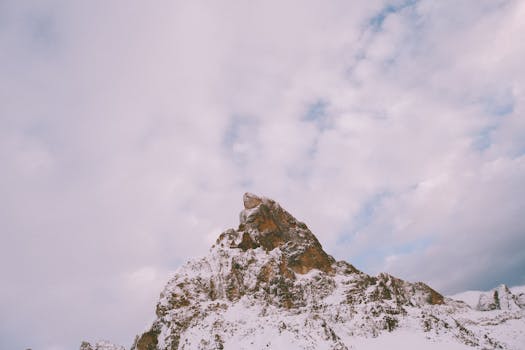 Breathtaking view of a snow-covered mountain peak against a cloudy sky.