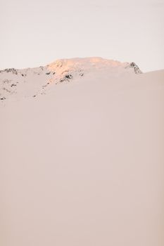 沐浴在柔和日出光线中的雪山，捕捉了冬季的宁静与祥和
