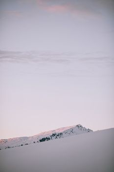 黎明时分，白雪覆盖的山峦在和平的冬日景象中沐浴着晨光