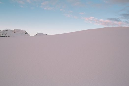 Peaceful snowy landscape with a clear sky at dawn, capturing the serene beauty of winter nature.