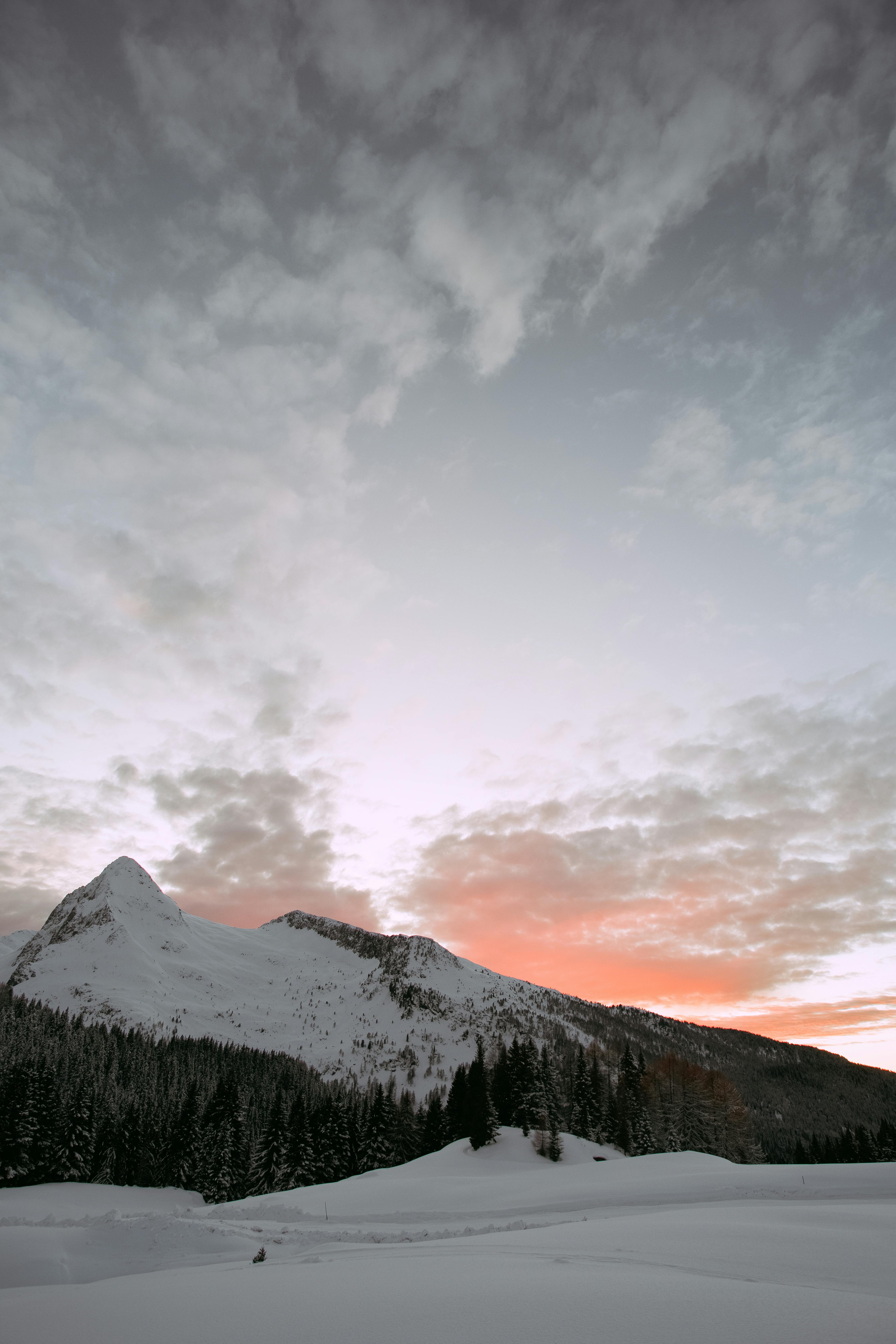 photo of snow covered mountain under cloudy sky