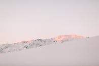 在温暖的日出色调下，宁静的雪山景观唤起了冬日的美丽与宁静