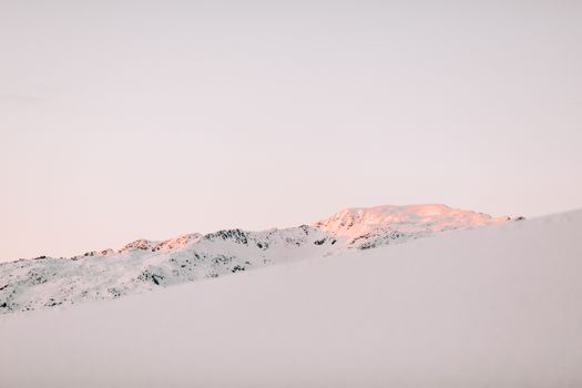 在温暖的日出色调下，宁静的雪山景观唤起了冬日的美丽与宁静