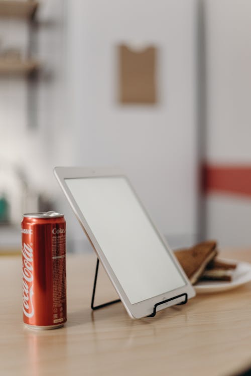 White Tablet Computer Beside Red Coca Cola Can