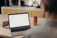 在家用办公桌前，膝上型计算机屏幕空白，旁边放着三明治和苏打水的人