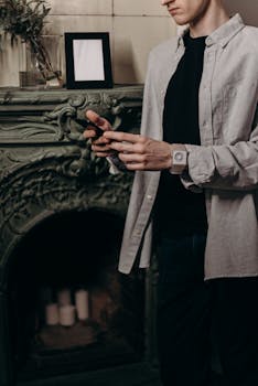 Man using smartphone in a cozy home office setup with stylish interior and decor.