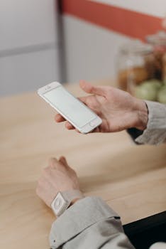 A minimalist setup showing a hand holding a smartphone with blank screen at a table.
