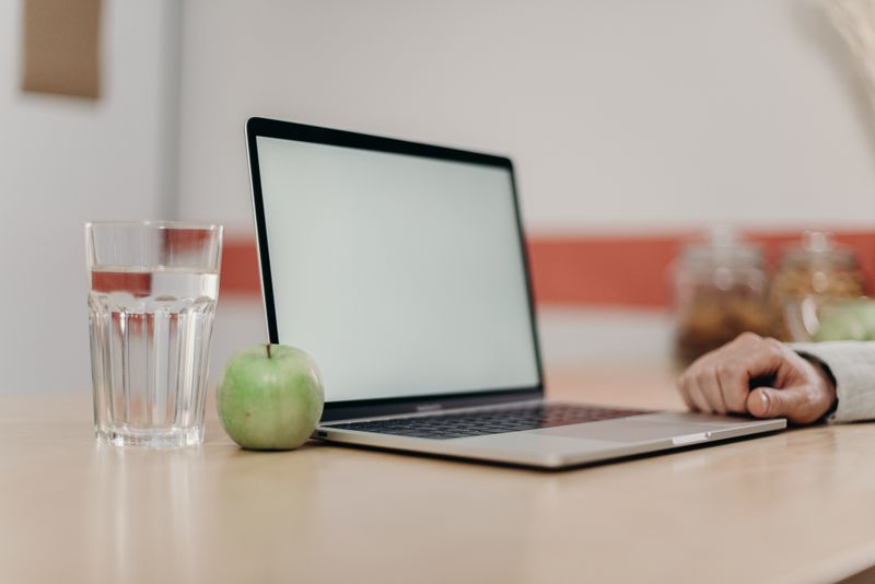 apple and orange on a desk next to a laptop