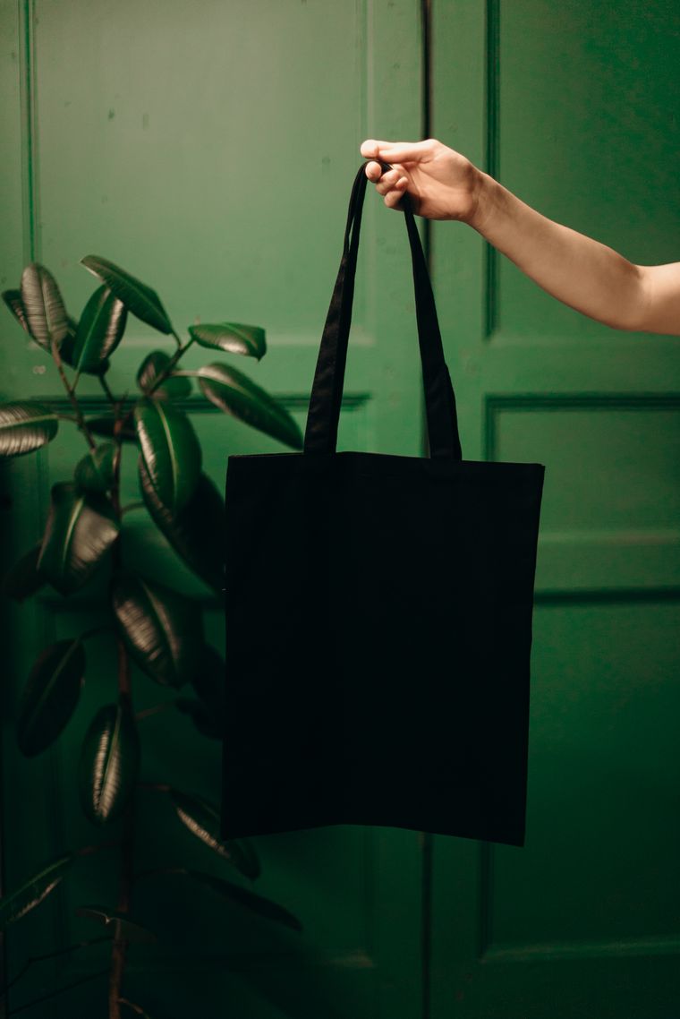 Plain black cotton tote held against a soft green backdrop - photo by cottonbro studio on Pexels