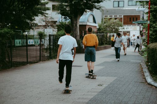 Man in White T-shirt and Black Pants Riding Skateboard on Sidewalk