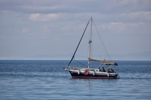 White and Red Boat on Sea Under Cloudy Sky