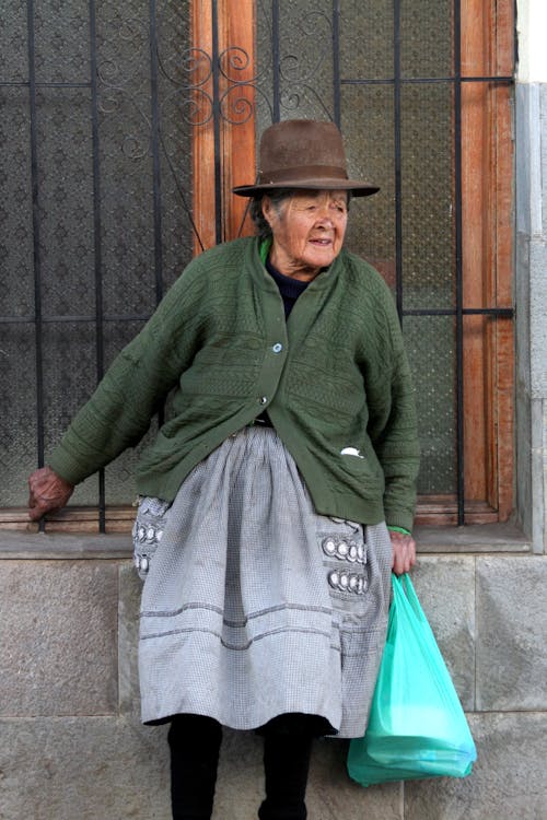 Woman in Green Cardigan and Gray Skirt Sitting on Concrete Bench